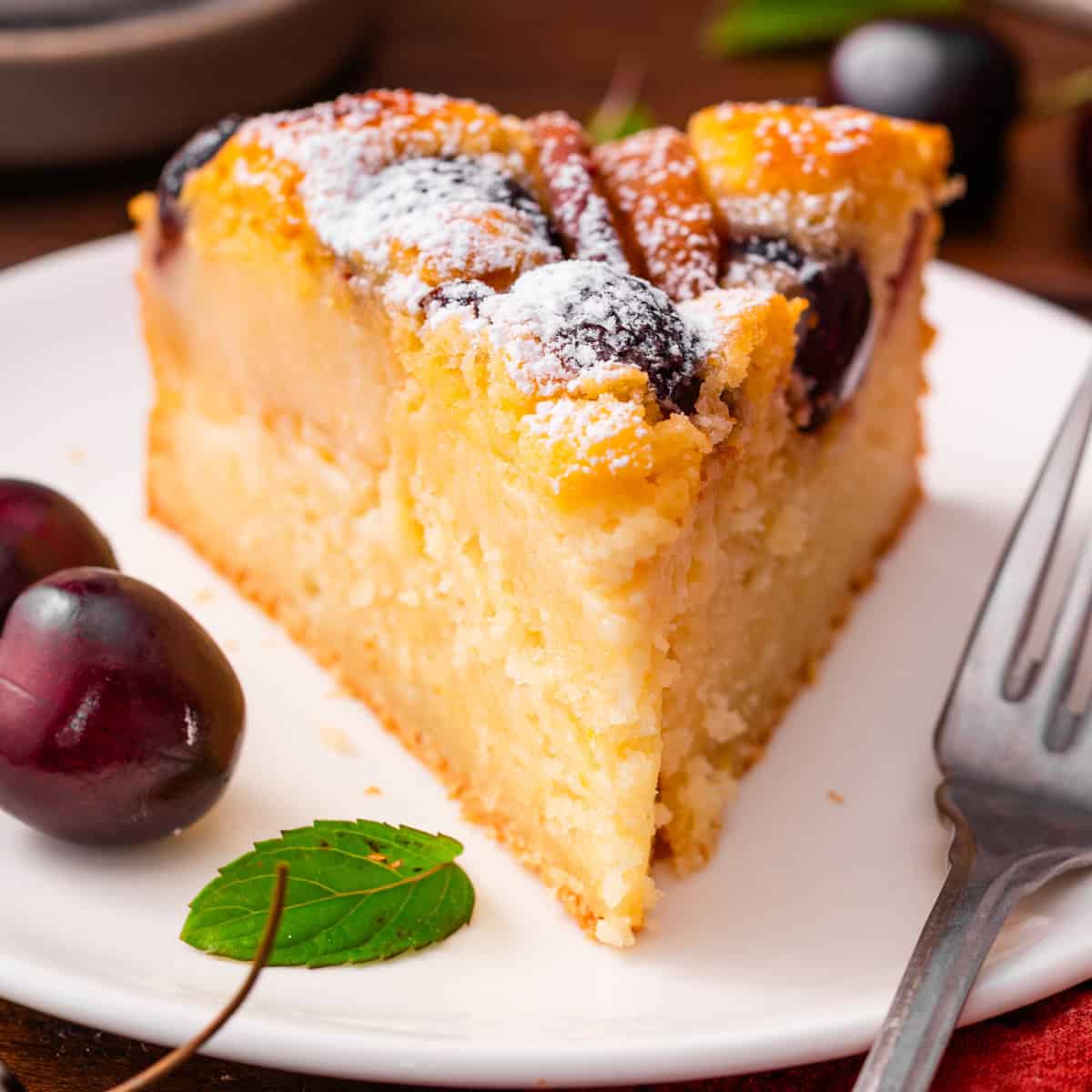 Italian-Style Lemon Ricotta Cake with Cherries and Peaches A slice of Italian-Style Lemon Ricotta Cake with Cherries and Peaches dusted with powdered sugar.