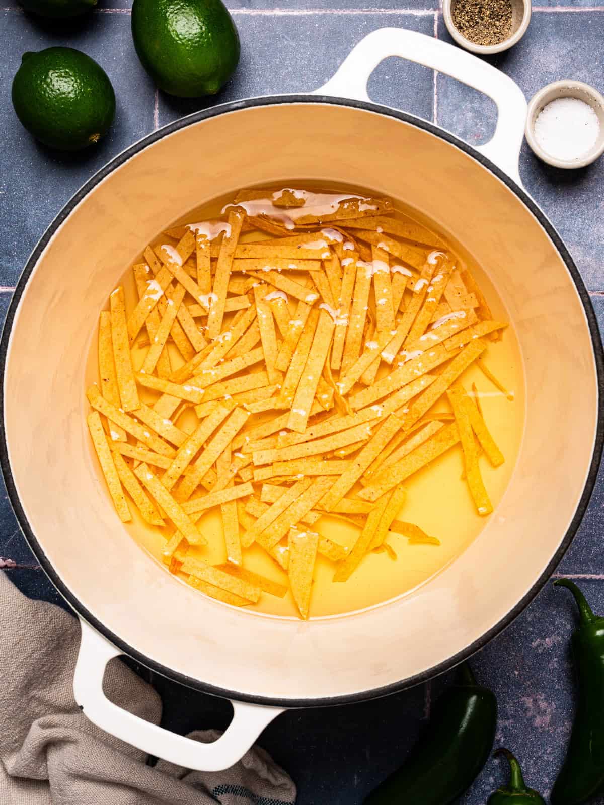 Chicken Tortilla Soup Corn tortilla strips frying in oil inside a white pot.