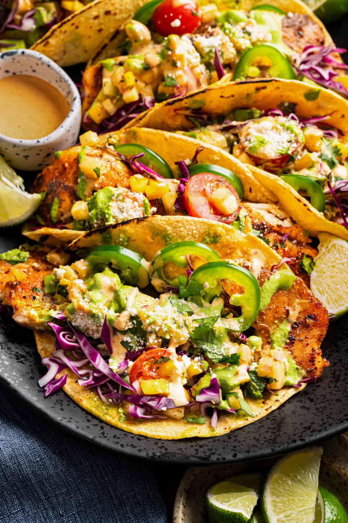 Corn tacos filled with grilled fish, avocado, sliced jalape&ntilde;os, cherry tomatoes, cabbage, served with lime wedges.
