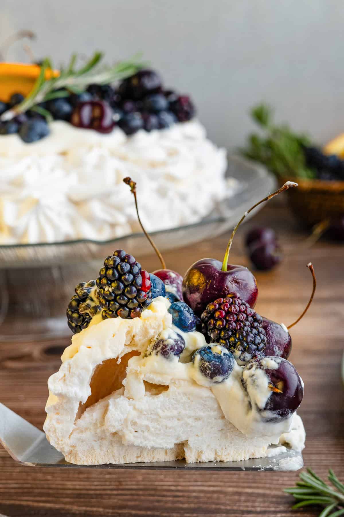 A slice of pavlova topped with cherries, blackberries, and blueberries.