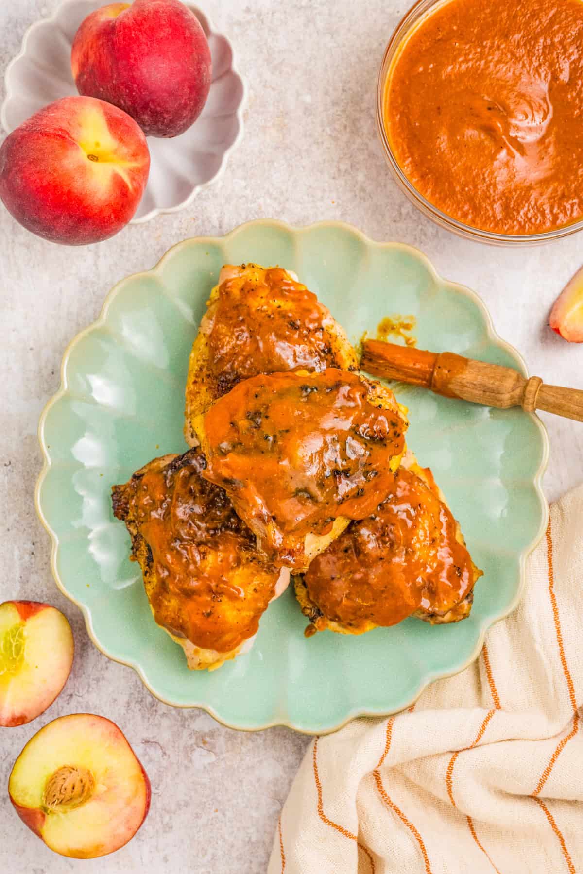 Three pieces of chicken with peach barbecue sauce on a green plate.