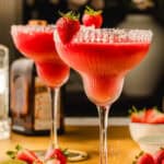 Two strawberry margaritas in salt-rimmed glasses, each garnished with a whole strawberry.