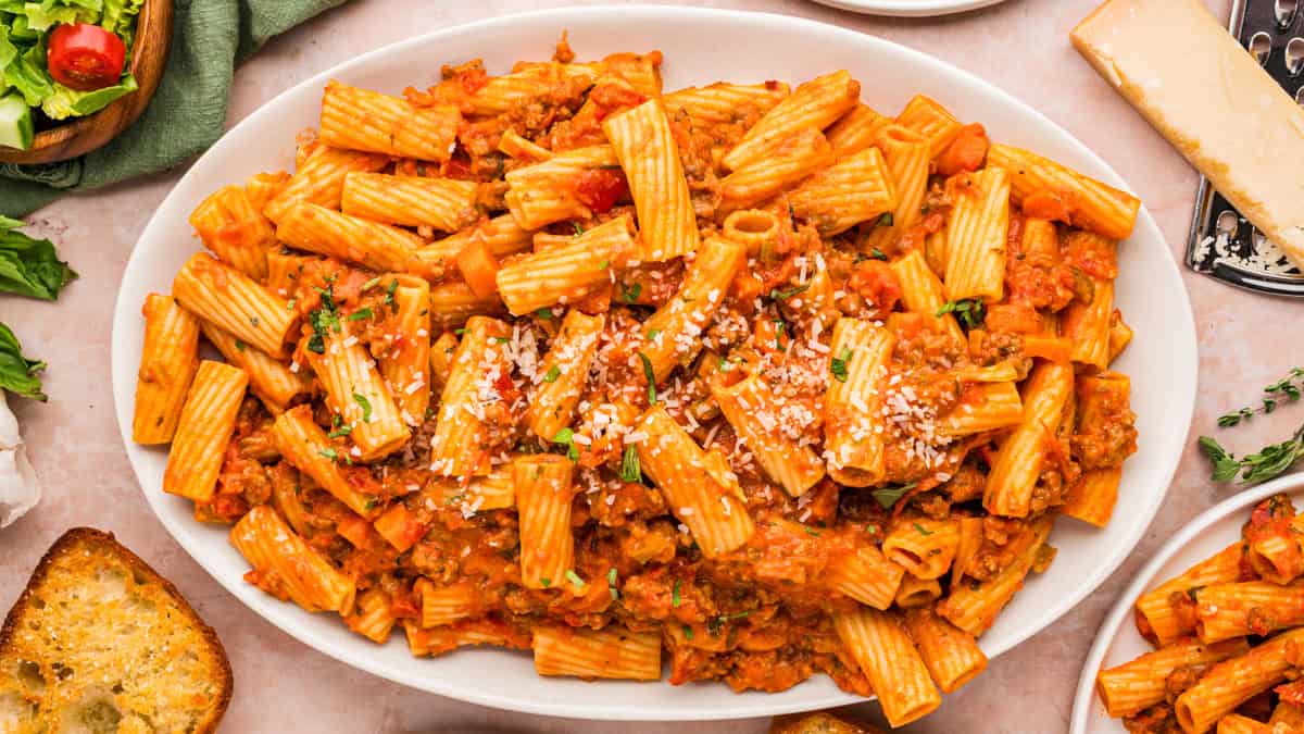Sausage Ragu Oval white dish filled with rigatoni pasta in a red meat sauce, topped with grated cheese and herbs.