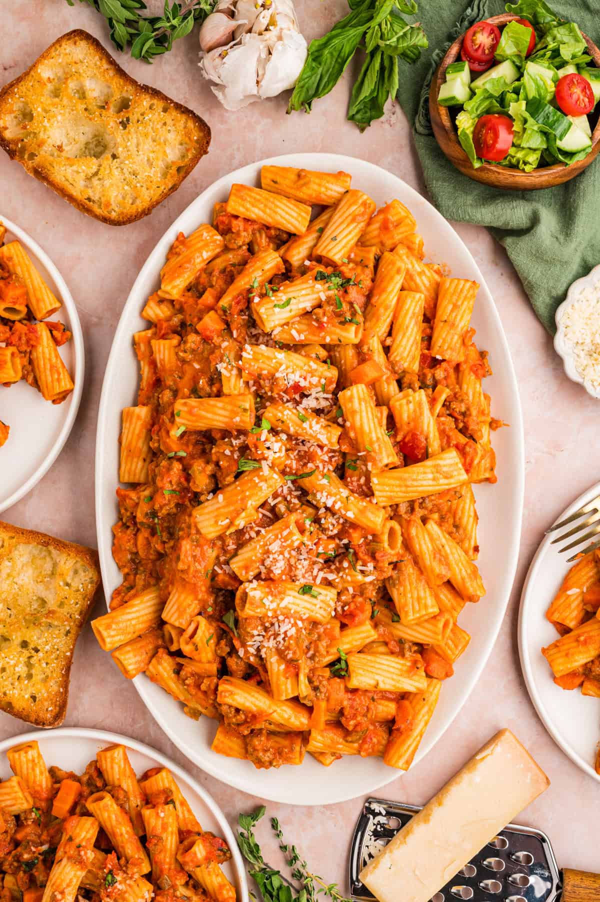 Sausage Ragu A platter of rigatoni pasta with tomato sauce, grated cheese, and herbs.