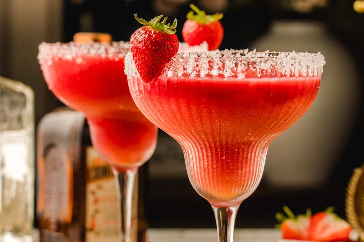 Strawberry Margarita Two glasses of strawberry margarita with salted rims, each garnished with a whole strawberry.