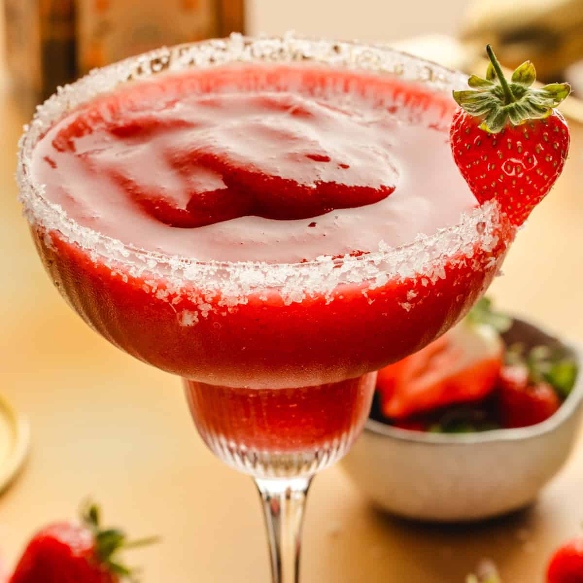 Strawberry Margarita A frozen strawberry margarita in a glass with a salted rim, garnished with a fresh strawberry.