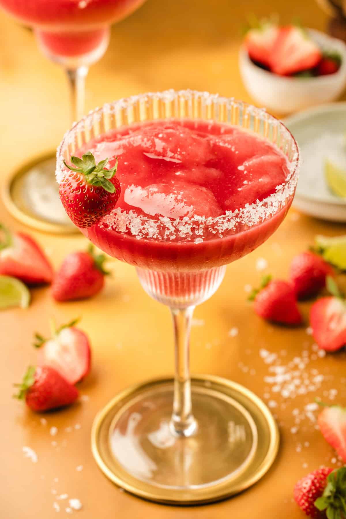 Strawberry Margarita A frozen strawberry margarita in a glass rimmed with salt, garnished with a fresh strawberry.