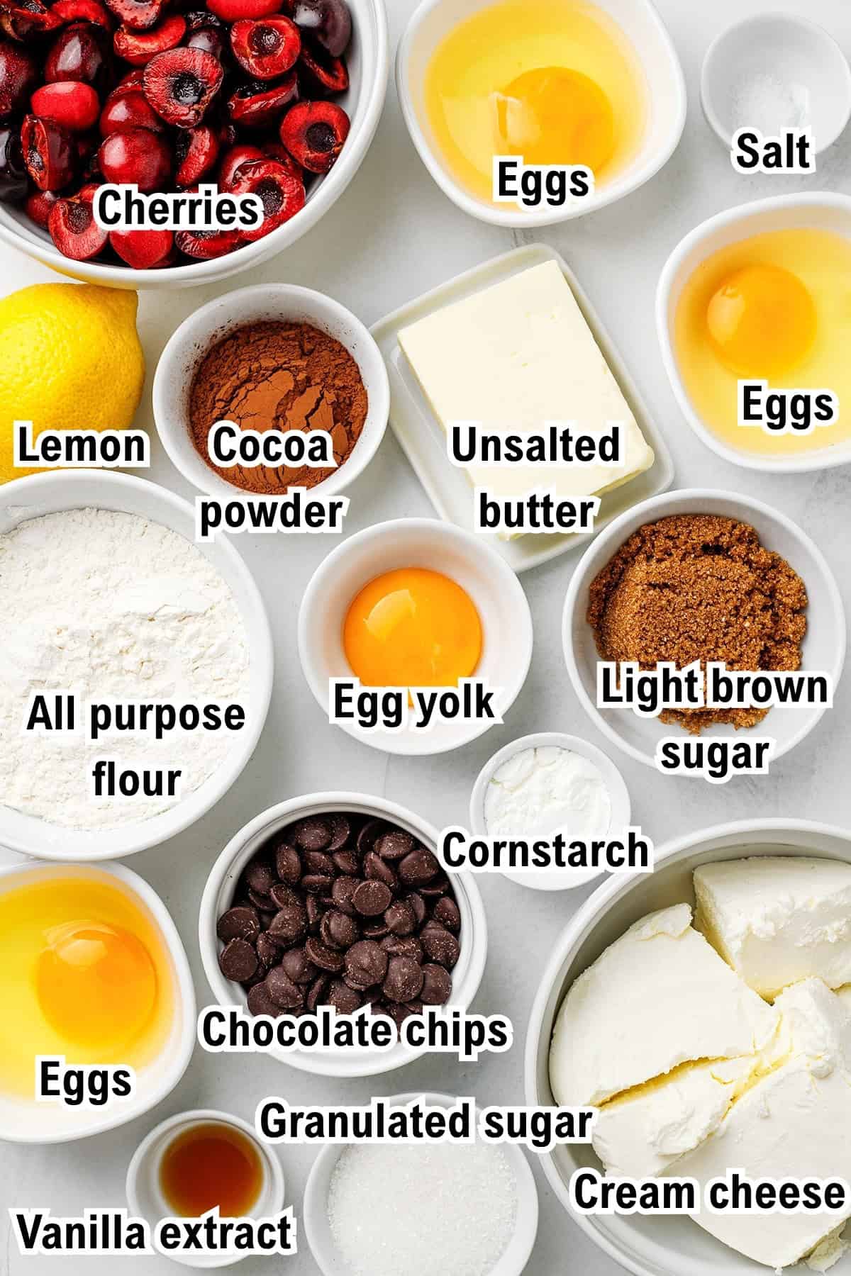 The Ingredients for Cherry Cheesecake Brownies This photo shows the ingredients for Cherry Cheesecake Brownies including cherries, eggs, salt, lemon, cocoa powder, unsalted butter, two types of sugar, egg yolk, flour, cornstarch, chocolate chips, cream cheese, and vanilla extract.