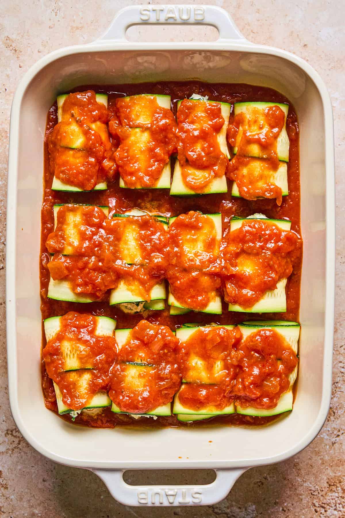 Zucchini Rollatini A baking dish filled with zucchini roll-ups topped with red tomato sauce.