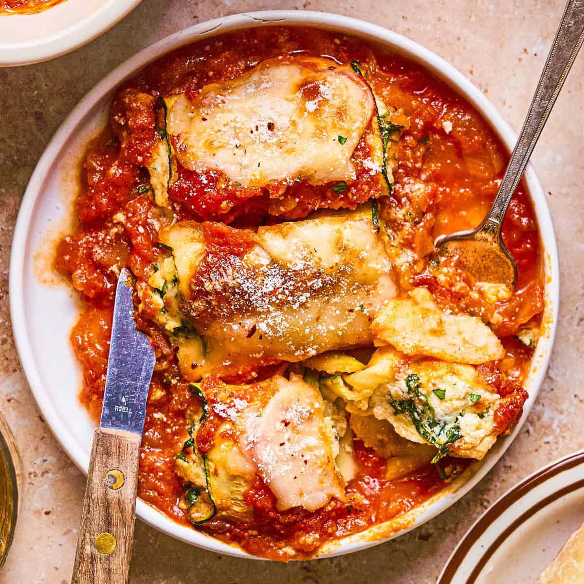 Zucchini Rollatini A plate of zucchini roll-ups with tomato sauce, and melted cheese.