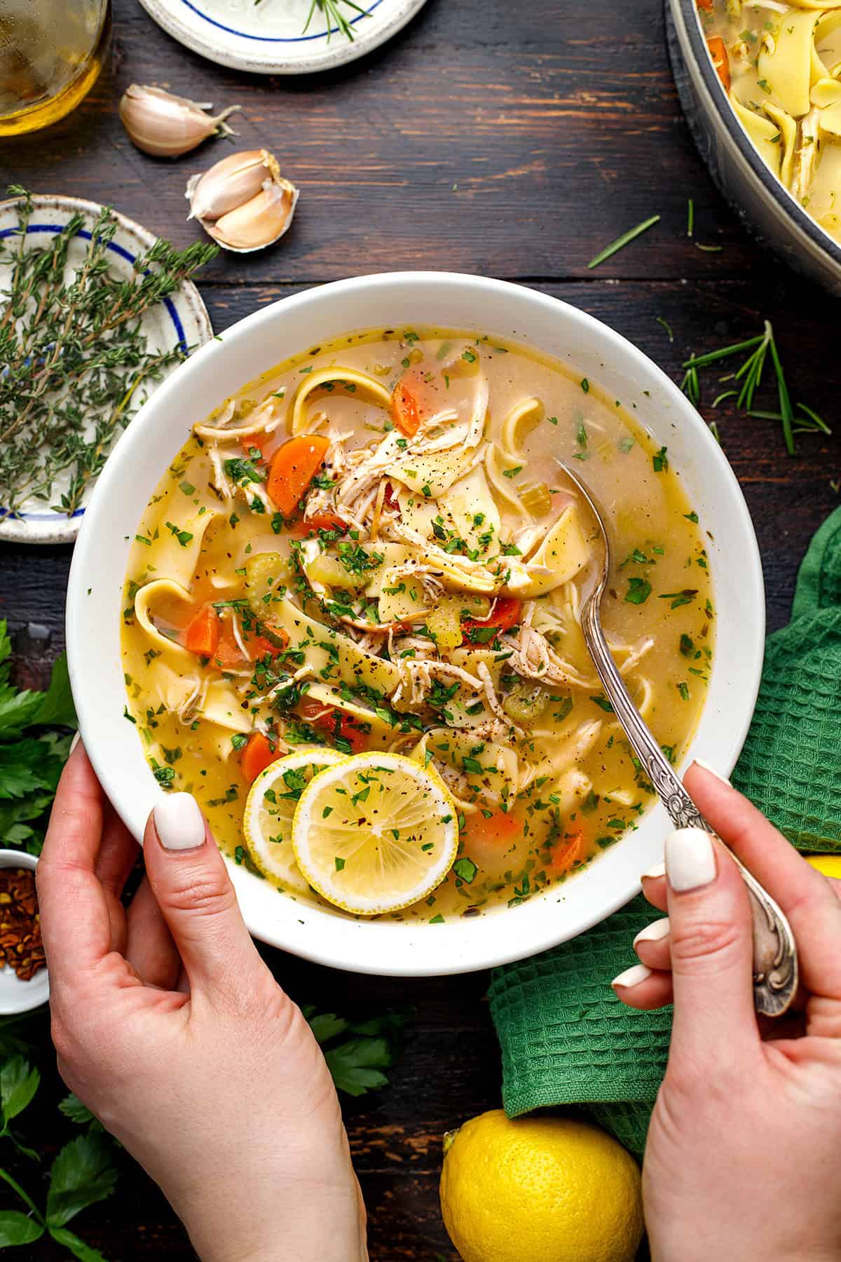Chicken Noodle Soup A bowl of chicken noodle soup with carrots, herbs, and lemon slices.
