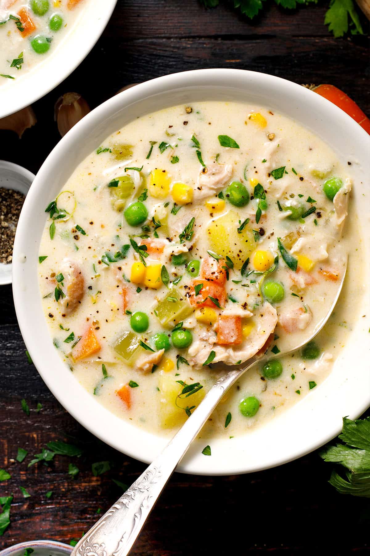 Chicken Pot Pie Soup A bowl of creamy chicken and vegetable soup with corn, peas, carrots, and potatoes, garnished with herbs.