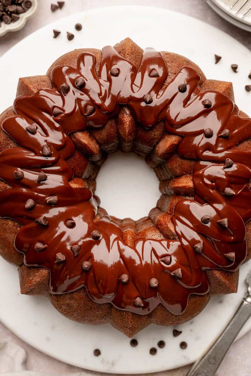 Chocolate bundt cake topped with glossy chocolate glaze and sprinkled with chocolate chips.