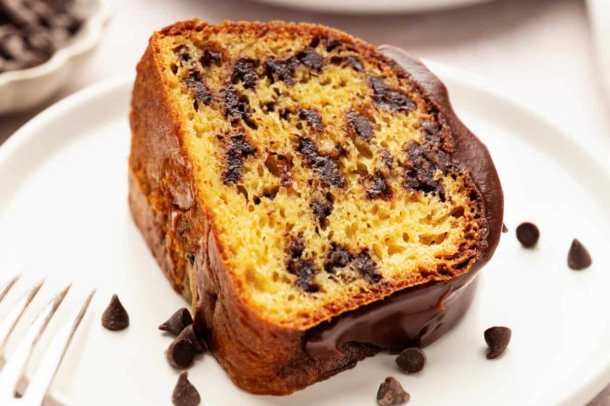 A slice of chocolate chip bundt cake with chocolate icing.