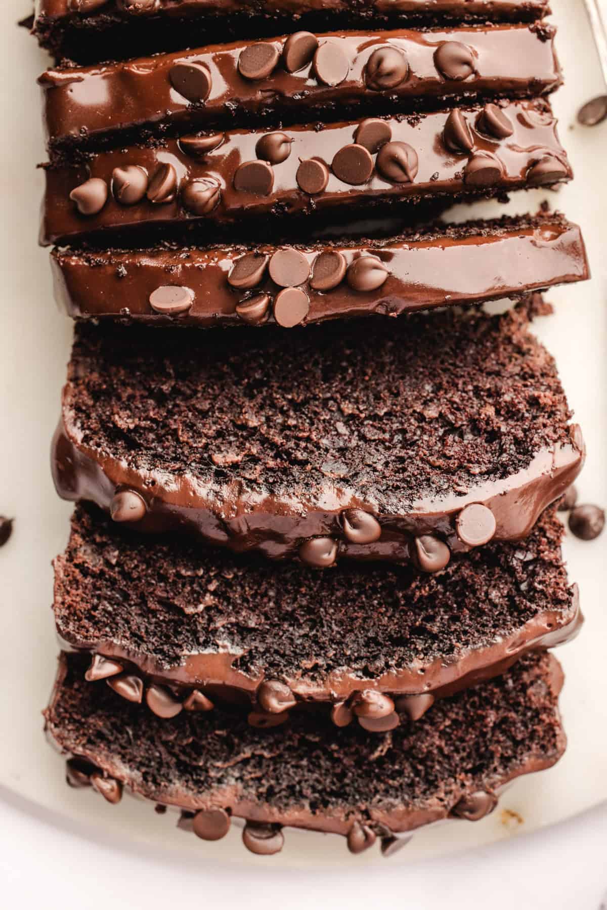 Chocolate Loaf Cake Sliced chocolate loaf cake topped with glossy chocolate glaze and sprinkled with chocolate chips.