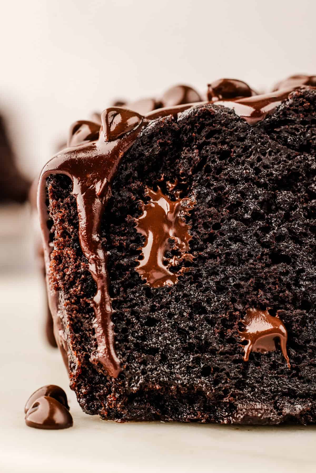 Chocolate Loaf Cake Close-up of a moist, dark chocolate loaf cake with melted chocolate chips and glossy chocolate glaze dripping down the side.