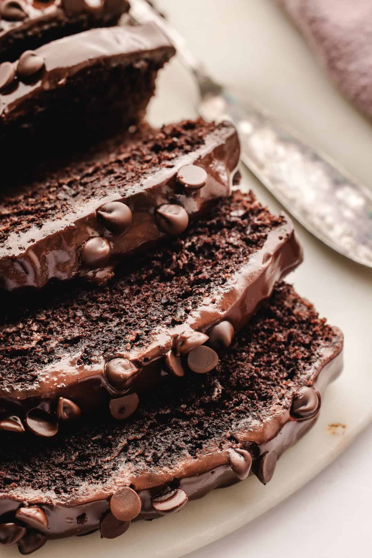 Chocolate Loaf Cake Close-up of several slices of rich, moist chocolate cake with chocolate chips and glossy chocolate frosting.