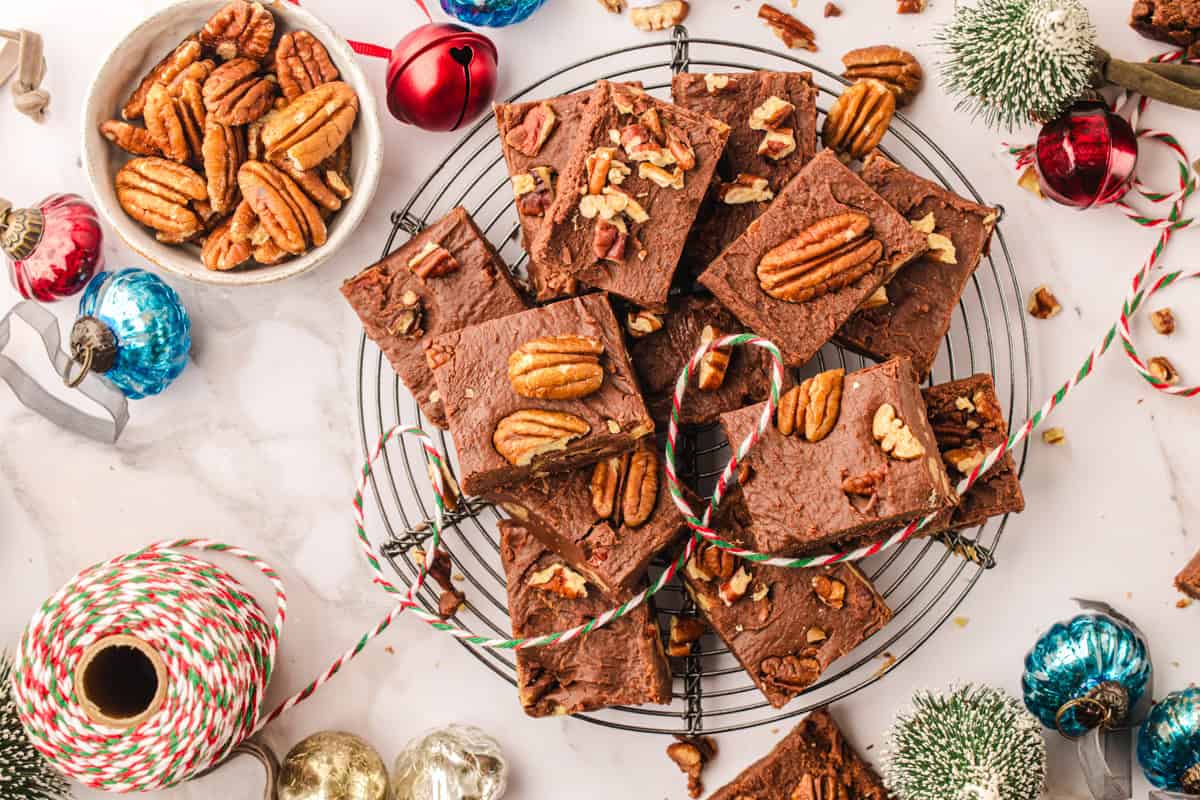 Fantasy Fudge Chocolate fudge topped with pecan halves are arranged on a cooling rack.