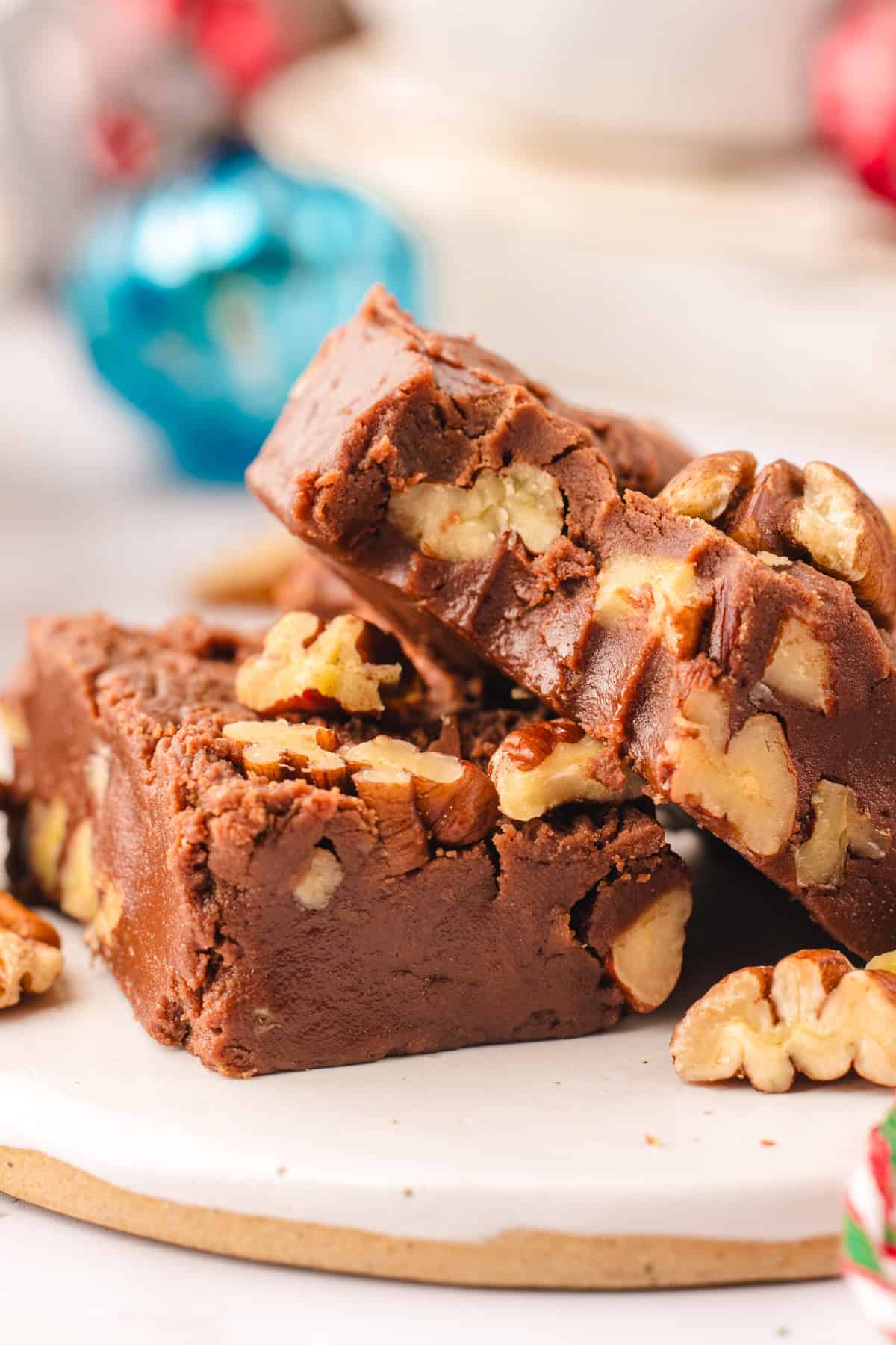 Fantasy Fudge Two pieces of chocolate fudge with visible pecan pieces stacked on a white plate.