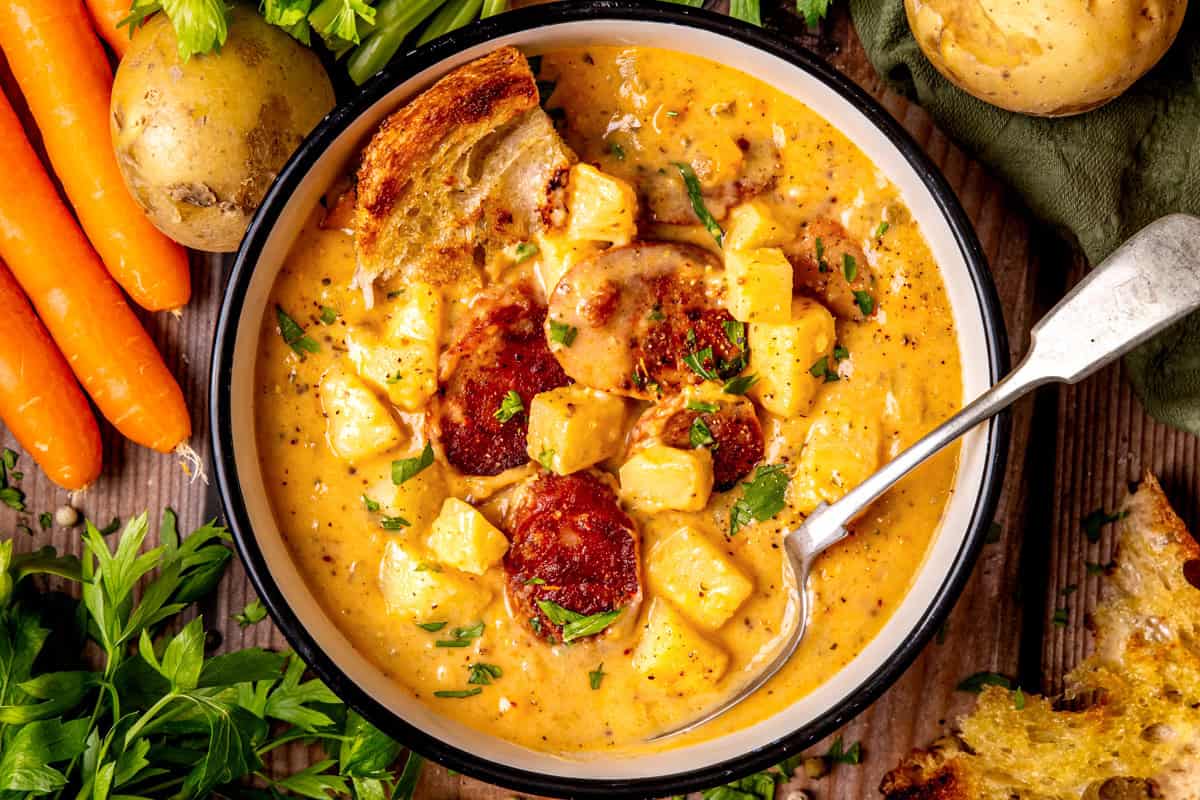 Kielbasa Potato Soup A bowl of creamy potato soup with sliced sausage, herbs, and chunks of bread.