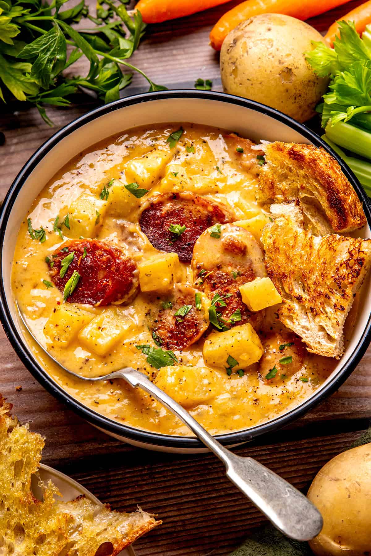 Kielbasa Potato Soup A bowl of creamy potato and sausage soup garnished with herbs, served with toasted bread.