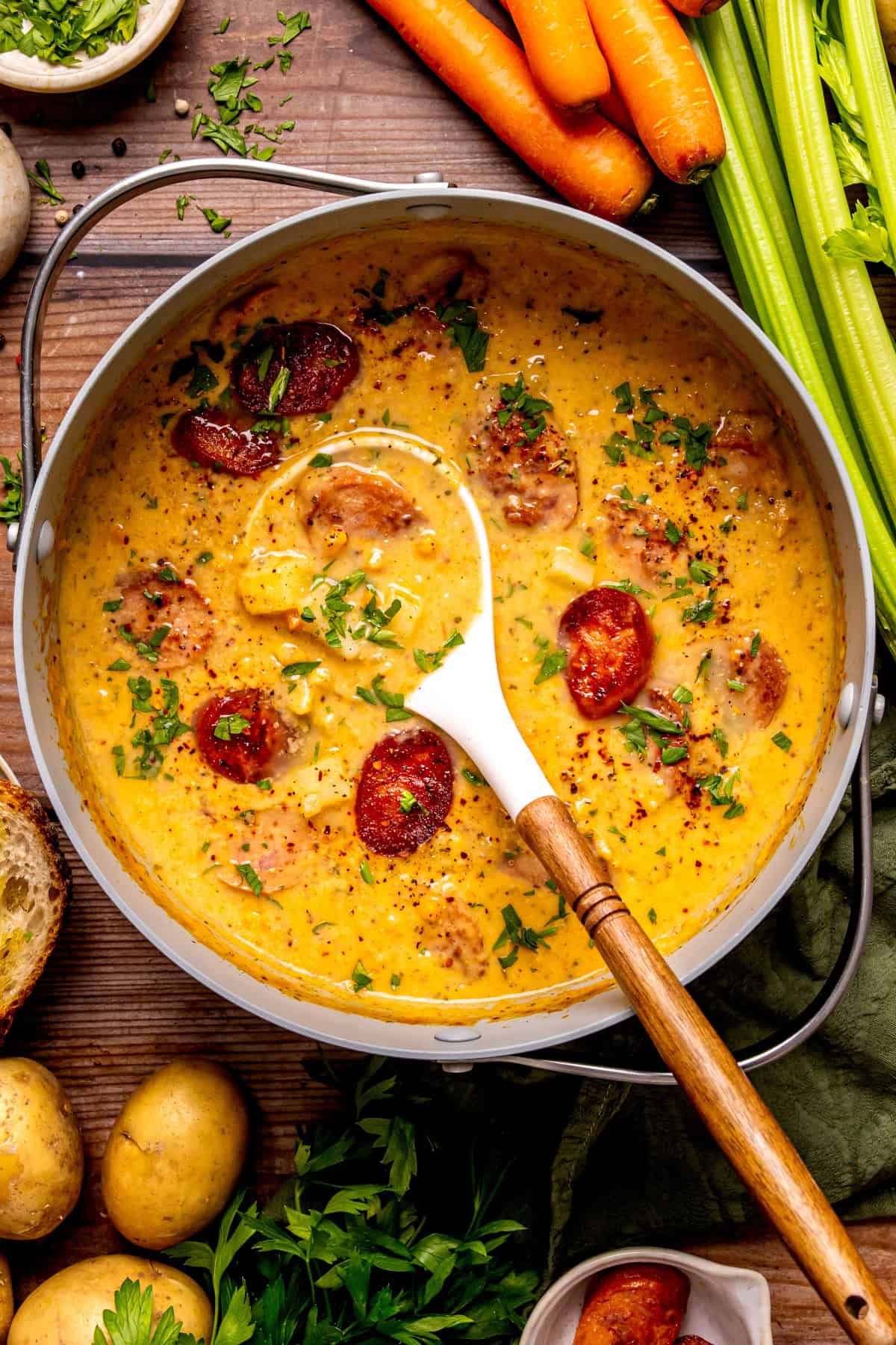 Kielbasa Potato Soup A pot of creamy soup with sausage slices, potatoes, and herbs sits on a wooden table.