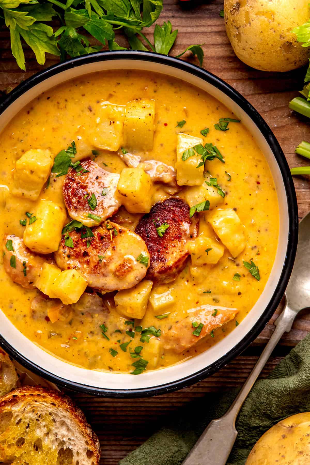 Kielbasa Potato Soup A bowl of creamy soup with chunks of sausage and potatoes, garnished with chopped parsley.
