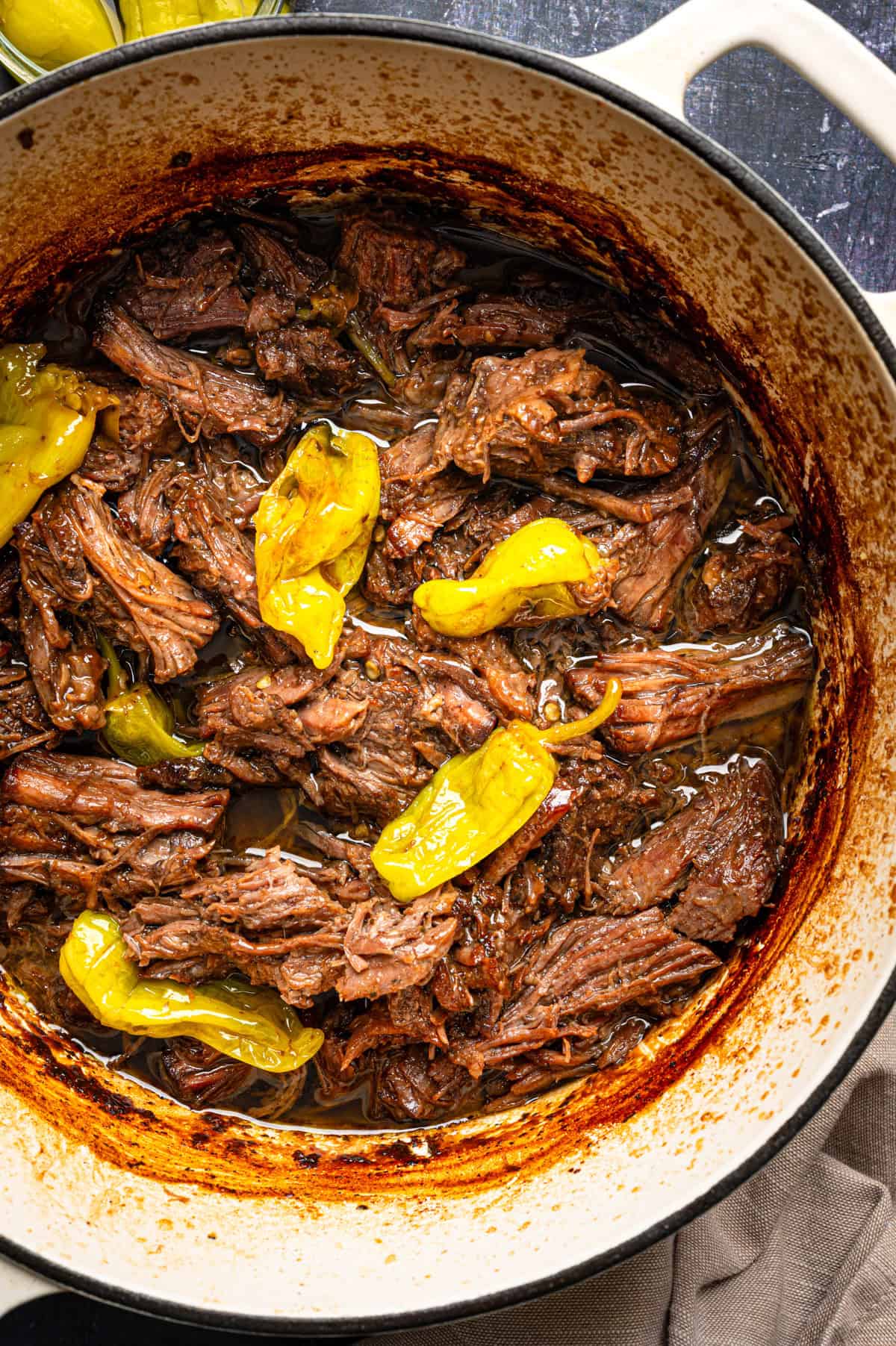 Mississippi Pot Roast (Easy Oven-Braised Chuck Roast) Shredded beef roast with juices and sliced yellow pepperoncini peppers.