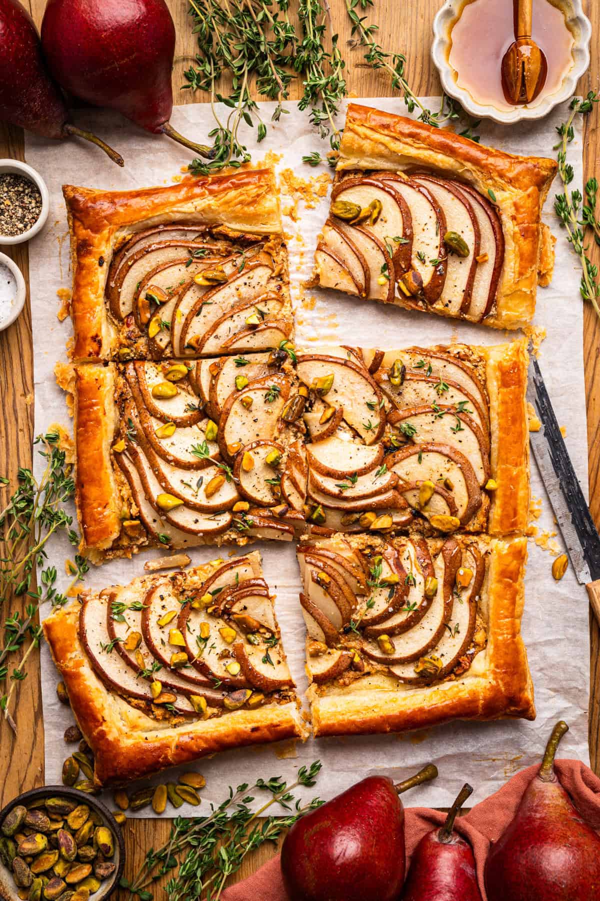 Pear Tart Rectangular pear tart with golden crust, topped with sliced pears and pistachios, cut into six pieces.