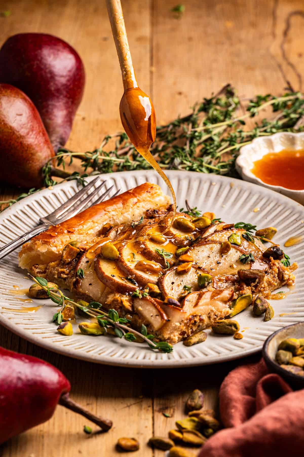 Pear Tart A slice of pear tart topped with pistachios and thyme is drizzled with honey.