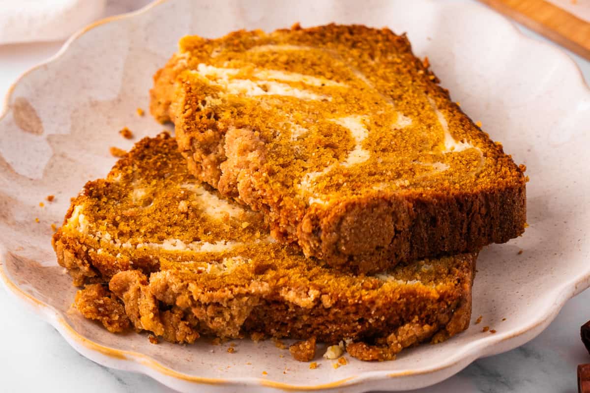 Pumpkin Cream Cheese Bread Two slices of pumpkin bread with a cream cheese swirl and crumb topping.