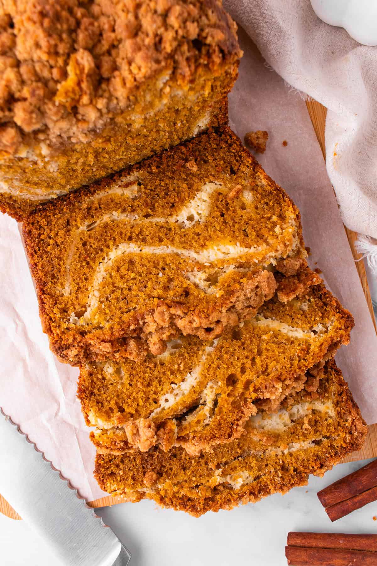 Pumpkin Cream Cheese Bread Sliced pumpkin bread with a crumb topping, showing swirls of cream cheese filling.