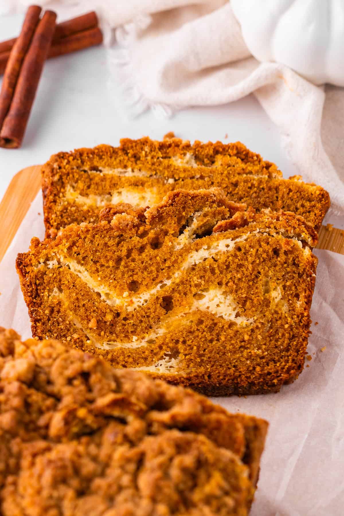 Pumpkin Cream Cheese Bread Two slices of pumpkin bread with a cream cheese swirl rest on parchment paper.