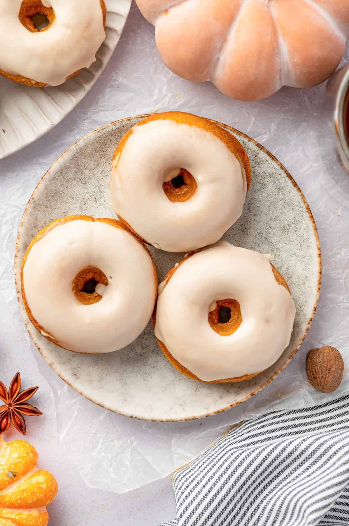 Pumpkin Spice Donuts Three frosted donuts on a round plate.