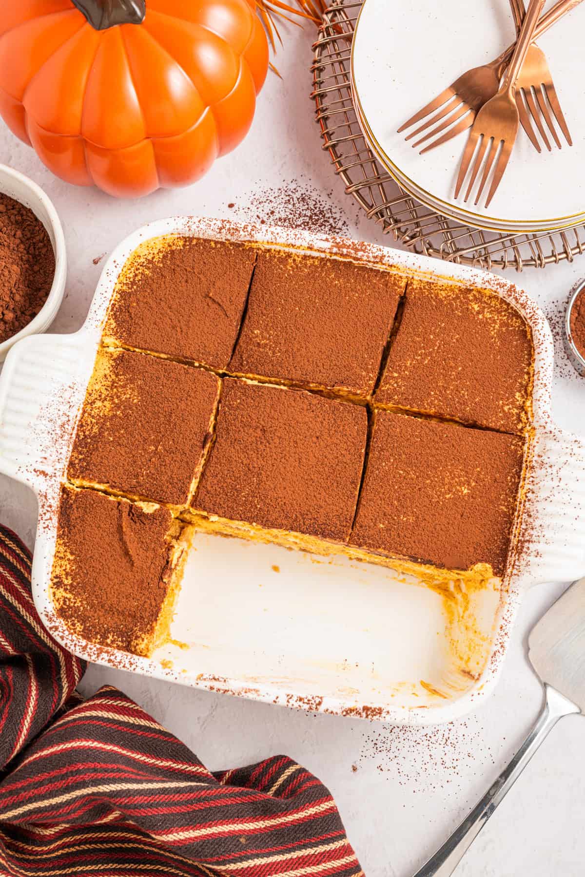 Pumpkin Tiramisu A white baking dish with nine pieces of pumpkin tiramisu, dusted with cocoa powder.