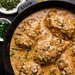 Chicken breasts cooked in a creamy mushroom sauce, garnished with chopped parsley.