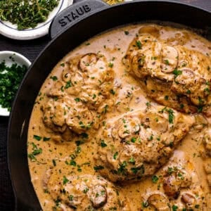 Chicken breasts cooked in a creamy mushroom sauce, garnished with chopped parsley.