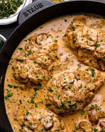 Chicken breasts in a creamy mushroom sauce, garnished with chopped parsley.