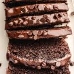 Sliced chocolate loaf cake topped with glossy chocolate frosting and chocolate chips.
