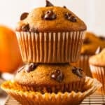 Two pumpkin chocolate chip muffins are stacked on top of each other, with chocolate chips visible on top.