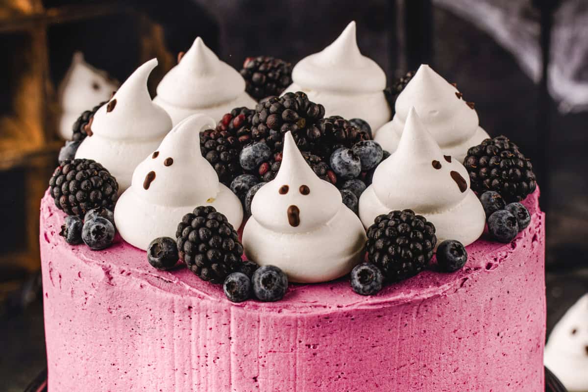 Halloween Cake A pink frosted cake topped with blackberries, blueberries, and meringue ghosts with chocolate faces.