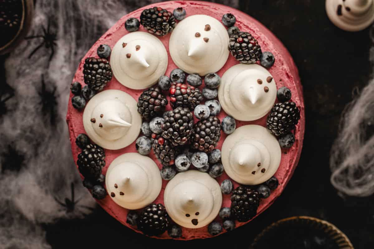 Halloween Cake A pink frosted cake decorated with meringue ghosts, blackberries, and blueberries, viewed from directly above.