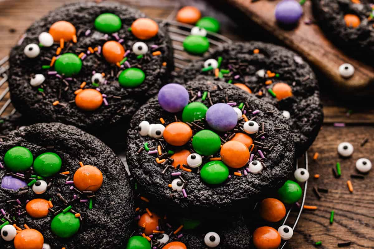 Dark chocolate cookies decorated with edible candy eyes and orange, green, and purple candy-coated chocolates.