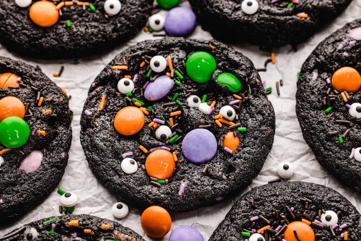 Halloween Cookies Several dark chocolate cookies decorated with colorful candy-coated chocolates, sprinkles, and edible candy eyeballs.