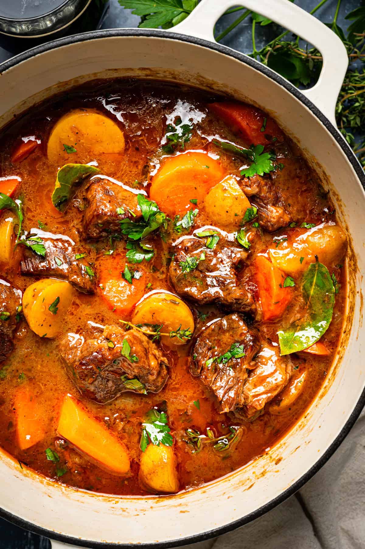 Irish Beef Stew Pot of beef stew containing chunks of meat, potatoes, and carrots, garnished with fresh herbs.