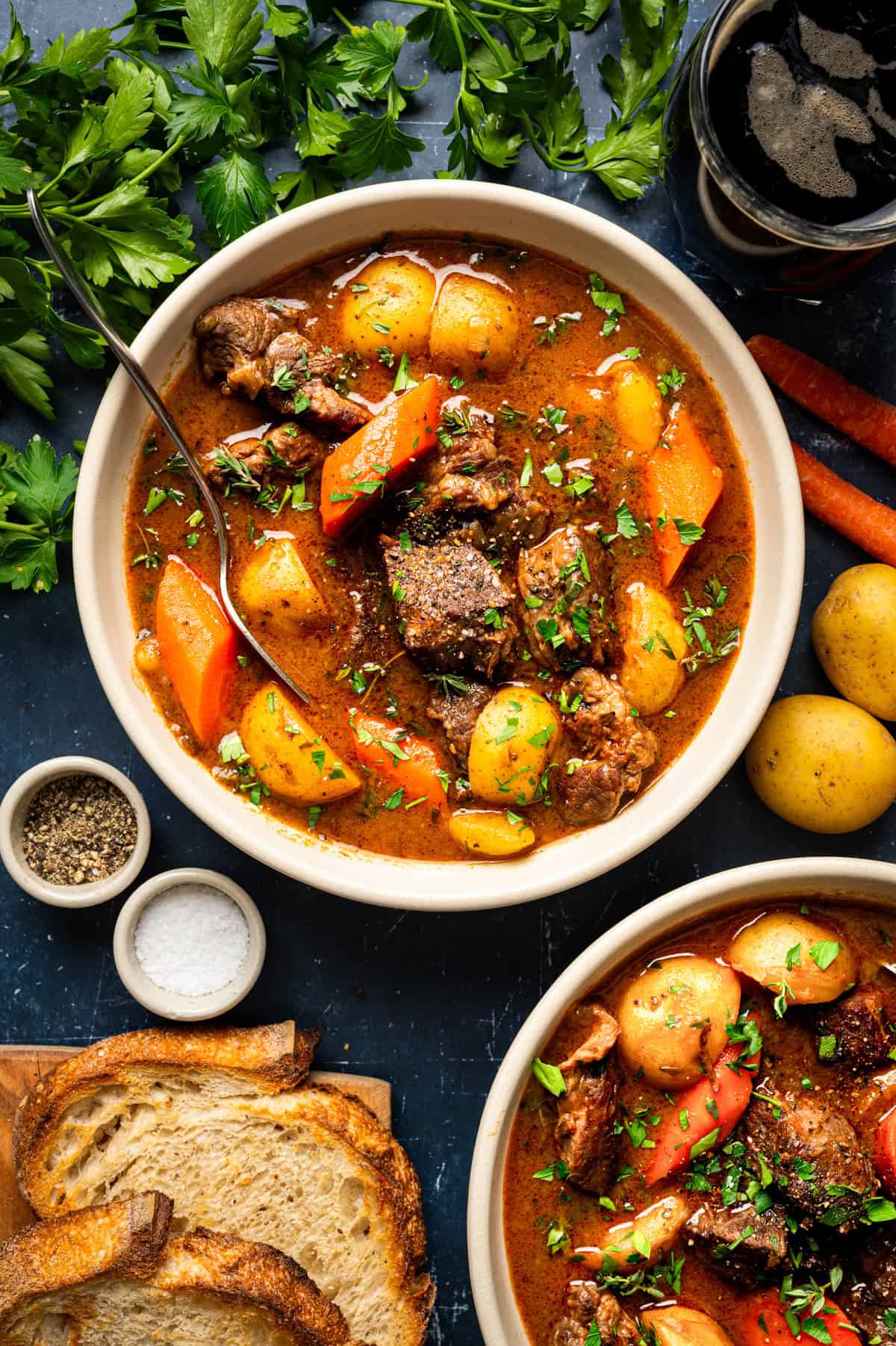 Irish Beef Stew Two bowls of beef stew with potatoes and carrots, garnished with herbs.