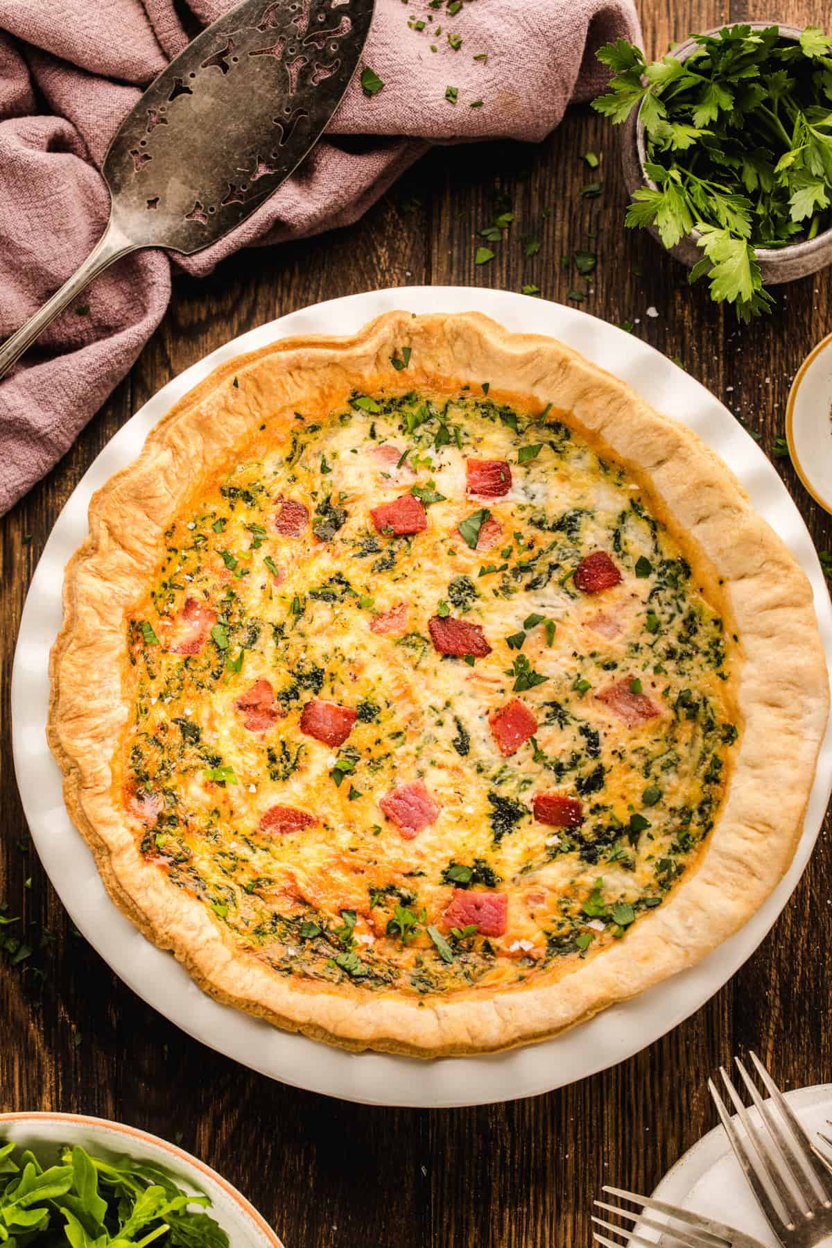 Quiche A spinach and bacon quiche in a flaky crust on a white plate.