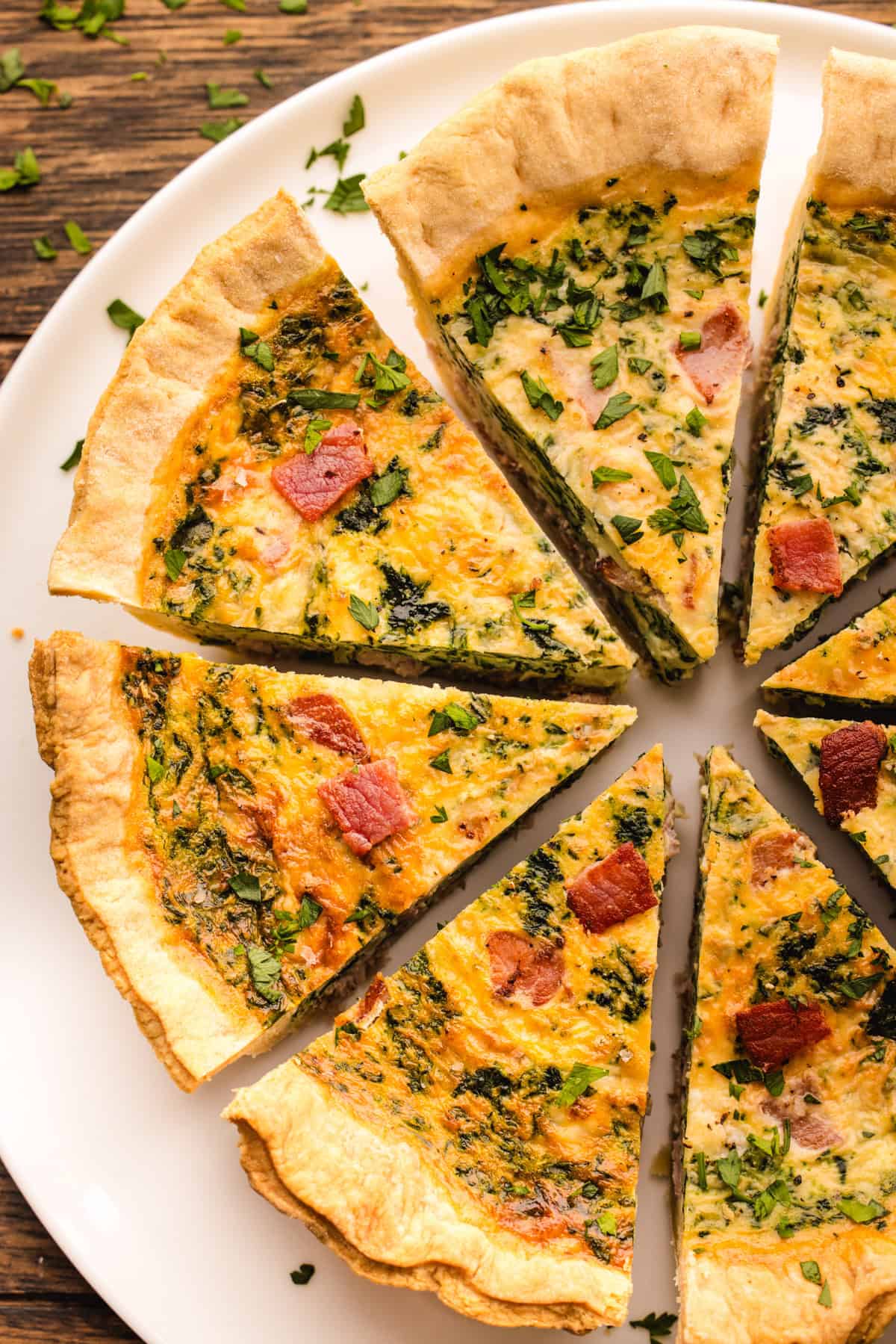 Quiche Slices of spinach, bacon, and cheese quiche arranged on a white plate.