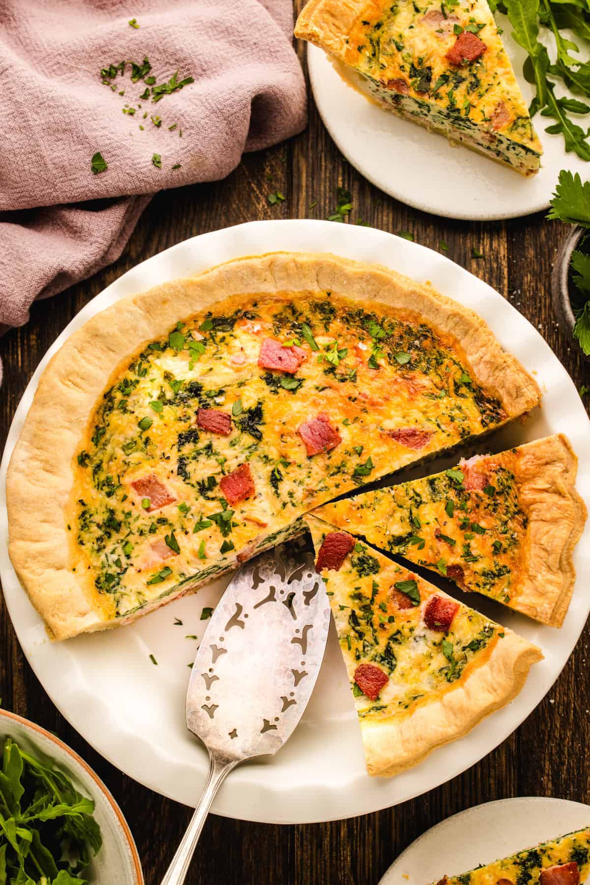 Quiche A savory quiche with bacon and herbs, sliced on a white plate.