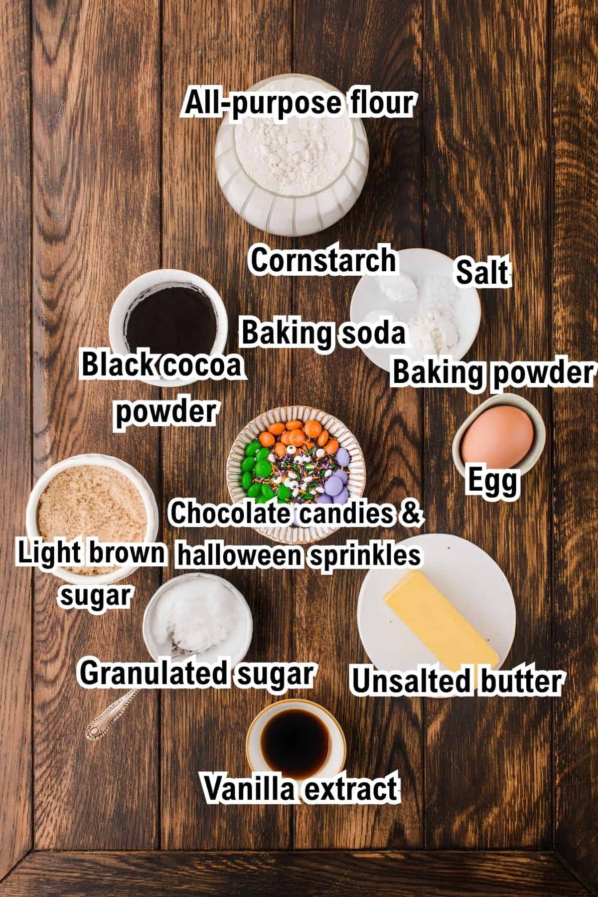 The Ingredients for Halloween Cookies This photo shows the ingredients for Halloween Cookies: bowls of flour, black cocoa, brown sugar, granulated sugar, salt, baking soda, baking powder, vanilla extract, butter, an egg, and a bowl of Halloween-themed candies and sprinkles.